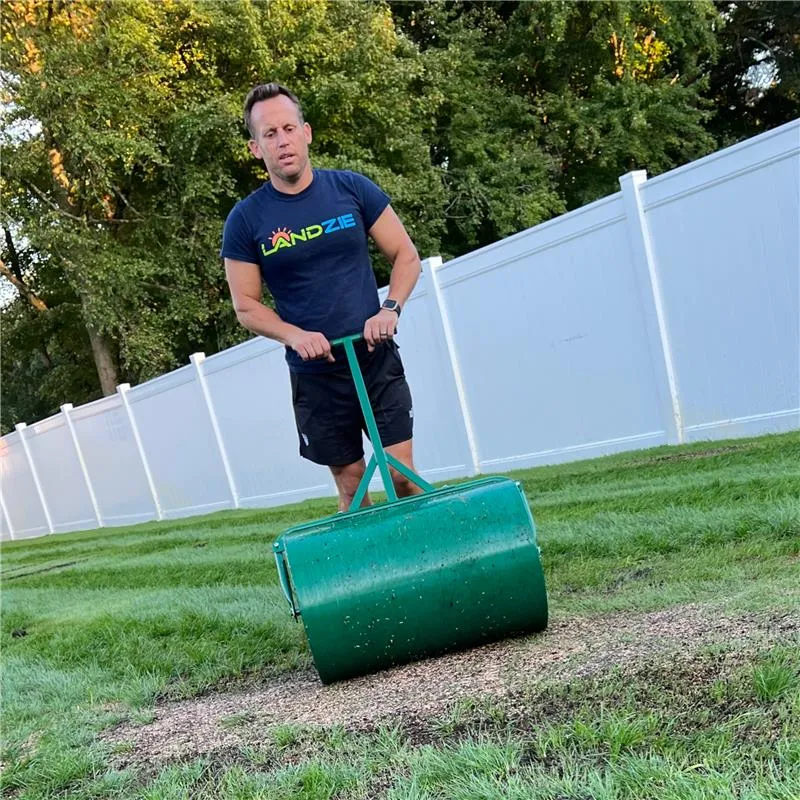 Andrew using the steel lawn roller to prepare the lawn for grass seed.